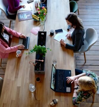 Overhead view of diverse women professionals working in a modern office setting, fostering collaboration and teamwork.