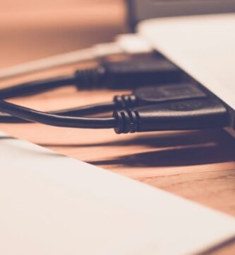 Close-up of laptop with cables on wooden desk, soft focus.
