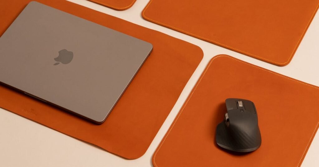 Stylish desktop featuring a laptop and mouse on leather pads, showcasing modern work essentials.