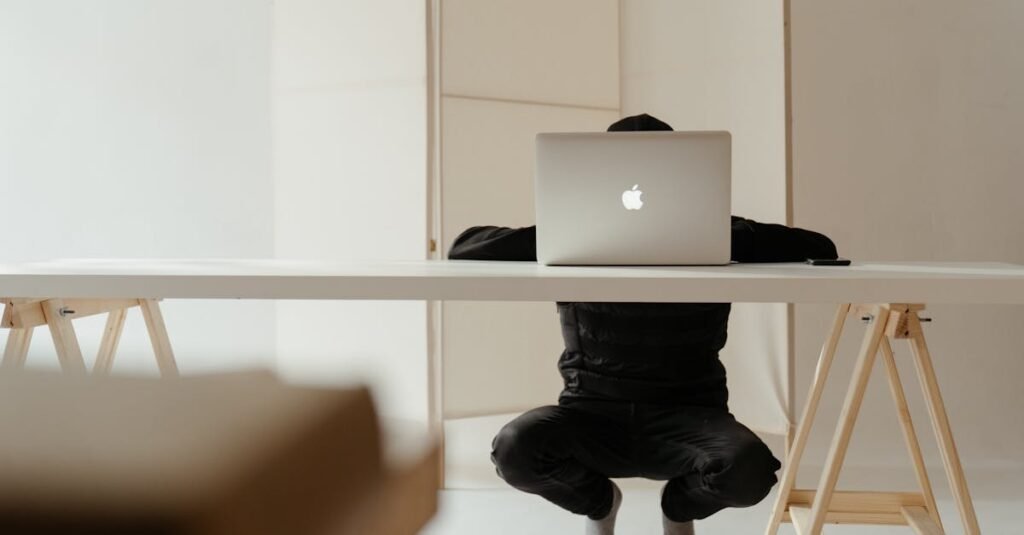 A person working in a minimalistic home office setup with a laptop on a white table.