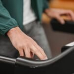 Crop anonymous male in activewear checking speed and time of treadmill on blurred background